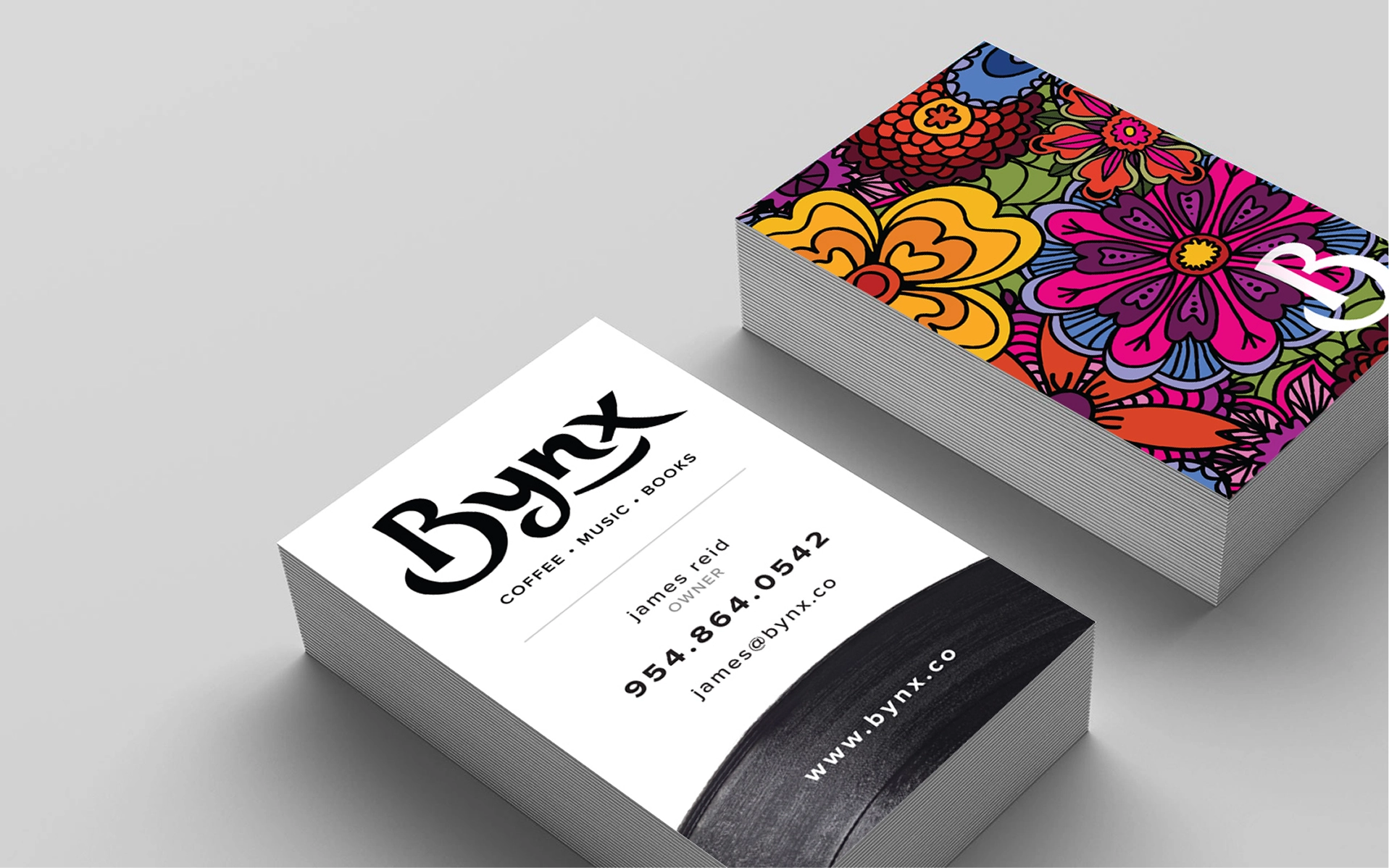 Bynx business cards with the logo on white and a psychedelic floral pattern on the back